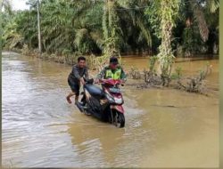 KOREM 012/TU : Anggota Babinsa Koramil 02/Woyla Bantu Dorong Motor Warga Melintasi Banjir